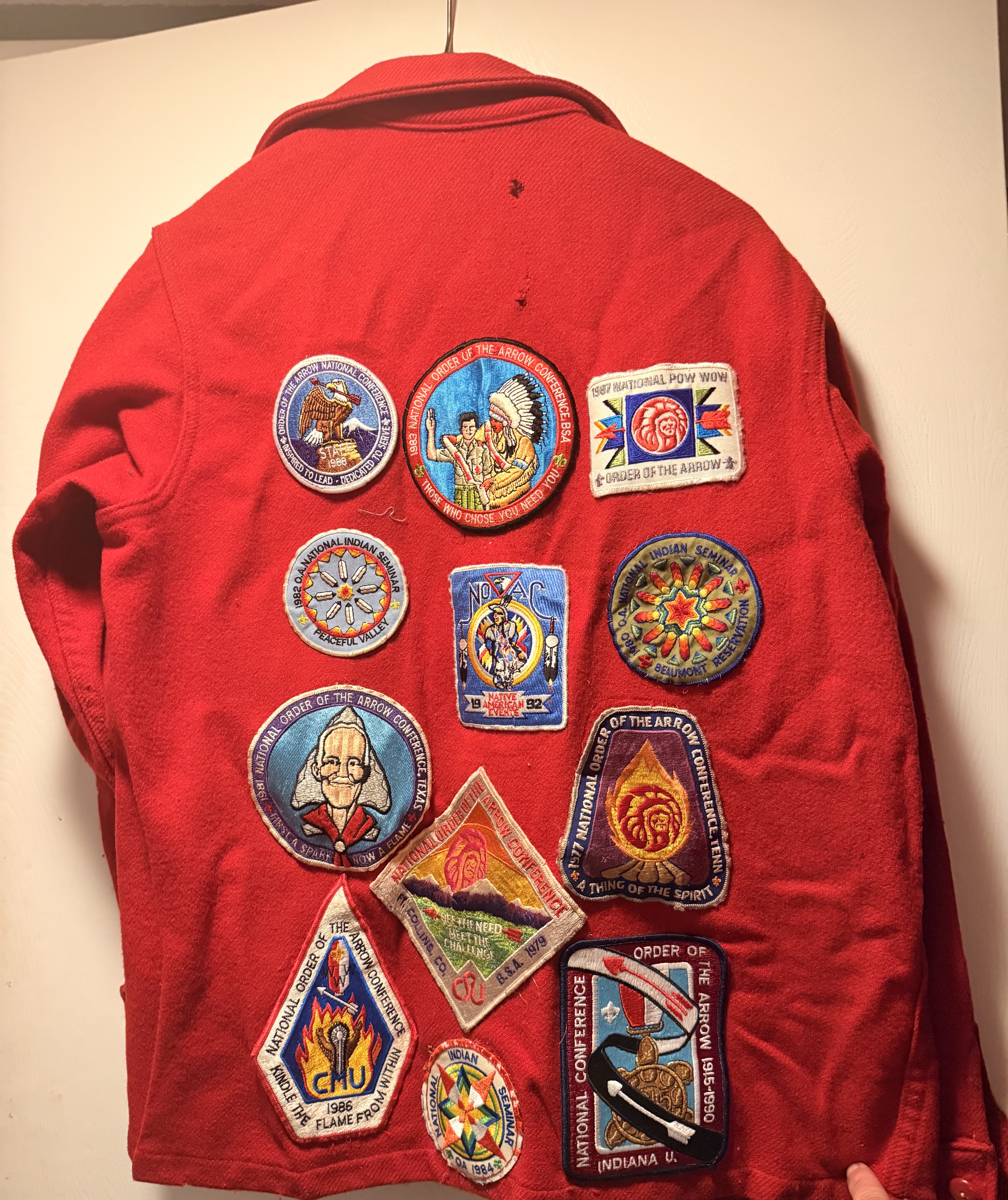 Red BSA wool jacket covered in National Order of the Arrow conference and seminar patches · 1977–1992